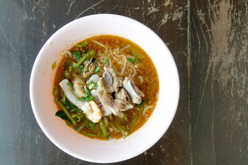 Spicy seafood noodles soup with pork bone crayfish, shrimp.  Asia food in pink bowl on wooden table background. Thai style noodle and street food of Thailand.   top view