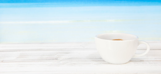 Coffee cup on white wood table with bright blue sea background