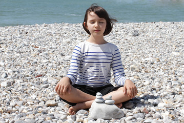 Fototapeta na wymiar happy child meditating on a mineral beach for relaxation and energy