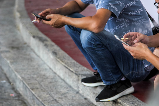 smoking man sitting on stairs and using phone