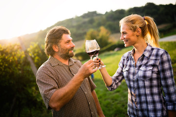 People tasting wine in vineyard and smiling