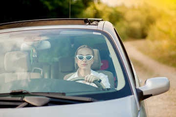 Portrait shot through windshield of pretty woman in car