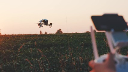 Hands farmer controls smart agriculture drone flying in sky at sunset rural aerial helicopter agros copter farm field industry landscape meadow nature plant vehicle harvest innovation slow motion