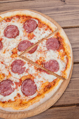 Italian Pepperoni pizza with salami on dark wooden background top view. Italian traditional food. Popular street food