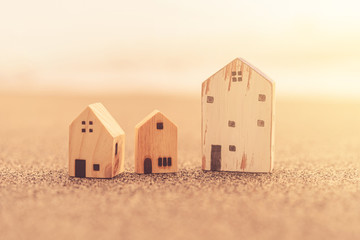 Small home model on sunset beach sand texture background.