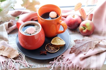Two cups of coffee, meringues, pumpkins, apples, leaves, plaid on the background of the window, home comfort concept, Thanksgiving, autumn season