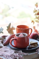 Two cups of coffee, meringues, pumpkins, apples, leaves, plaid on the background of the window, home comfort concept, Thanksgiving, autumn season