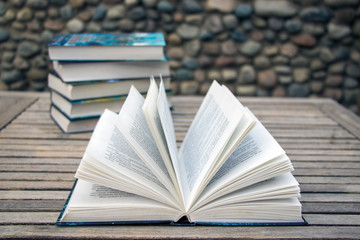 An open book and a stack of closed books in the back