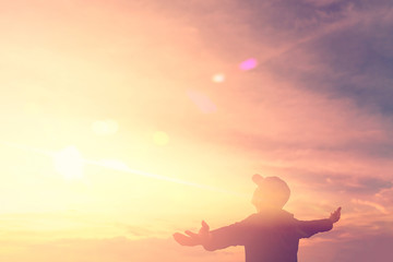 Copy space of silhouette man rising hands up on sunset sky and clouds abstract background.