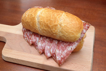 sandwich with italian salami on wooden cutting board
