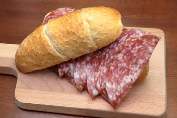 sandwich with italian salami on wooden cutting board