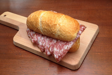 sandwich with italian salami on wooden cutting board