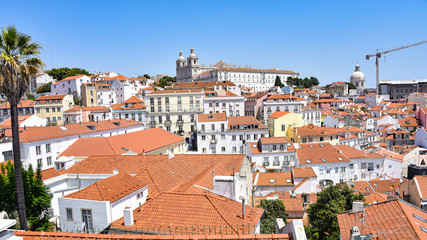 Fototapeta na wymiar Lisbon, Portugal - July 23, 2019: Summertime views across the rooftops of the Alfama district