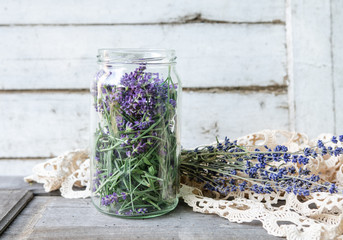 A glass jar full of freshly harvested lavender blossoms in vintage traditional environment