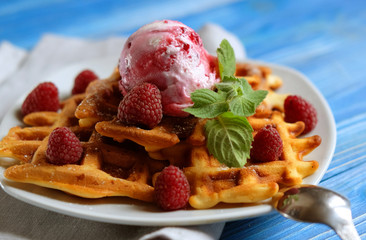 Plate of belgian waffles with ice cream and fresh berries over blue wooden background, top view