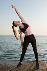 happy girl performs sport exercises, on the sea coast, morning, lifestyle