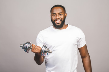 Fitness concept. Portrait of a happy african american black man with dumbbells isolated over grey...