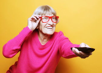 lifestyle and people concept: funny grandmother is holding a TV 