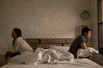 Asian couples quarrel sit in bed ,they argue not to talk to each other. They are unhappy - obrazy, fototapety, plakaty
