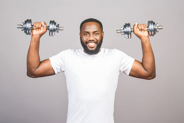 Naklejka na ściany i meble Fitness concept. Portrait of a happy african american black man with dumbbells isolated over grey background.