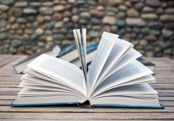 An open book and a stack of closed books in the back. 