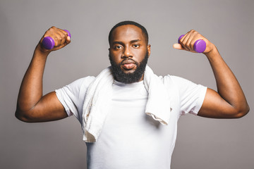 Fitness concept. Portrait of a happy african american black man with dumbbells isolated over grey background.