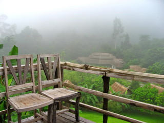 Fototapeta premium Old wooden chairs on wooden porch with green tree and fog in the morning. Object and nature concept.