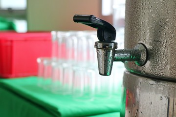 Water cooler with blurred glasses  on green table background at meeting room. Drink and object concept.