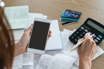 Woman holding mobile phone and using calculator , account and saving concept.