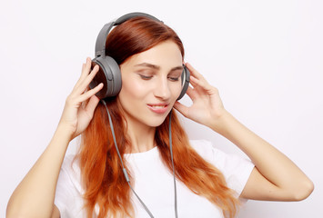 Fototapeta premium Beautiful redhair woman in headphones listening to music