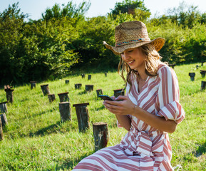 Smiling beautiful young woman in the park with cell phone