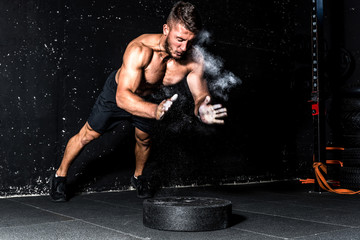 Young muscular man with big sweaty muscles doing push ups workout training with clap his hand above the barbell weight plate on the gym floor with motion blur