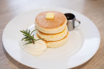 Honey pancakes and butter on the white dish.