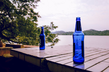 Two blue empty bottles of beer on the table outside near the river