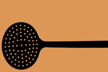 Foto di un mestolo usato in cucina su fondo arancione