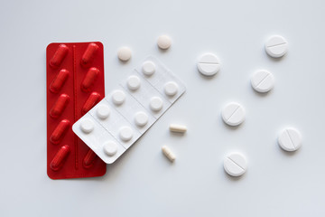 Medicine capsules and tablets  in red and white blister packs on a white background. Isolated. Copy space.