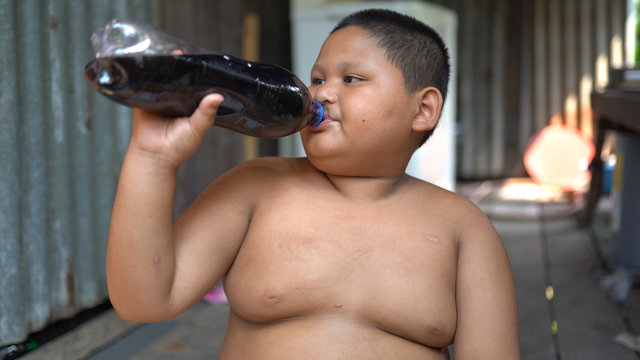 Fat boy is drinking a cola