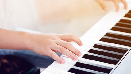 Close up of the hand An Asian girl is doing an activity to learn to play electric piano. Practicing music will give you good emotional skills; relax; good mental health and good mood. copy space