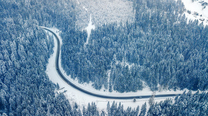 Aerial view of evergreen Christmass pine forest  and mountain asphalt road from above. bird's eye, drone shot. amazing natural winter background