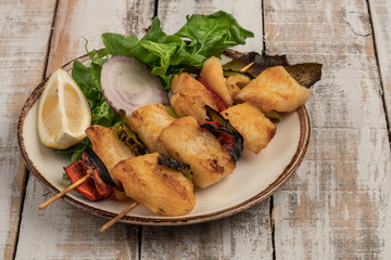 Skewed sole fish served with salad on table