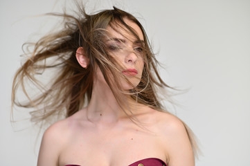 A close-up portrait of a cute girl, a young woman with beautiful curly hair on a white background with excellent face skin and outstanding fashionable make-up. Beauty, brightness.