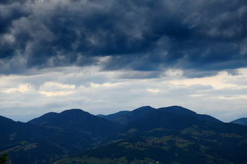 Naklejka premium Beautiful summer sunset and landscape - spruces on hills in the evening. Dark sky and silhouette of carpathian mountains. Ukraine. Europe. Travel background.