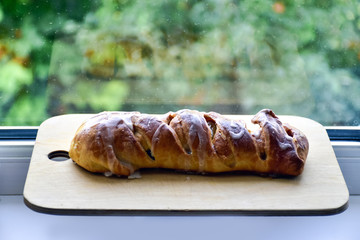 Homemade apple pie on a cutting wooden board, on a windowsill. Homemade baking.