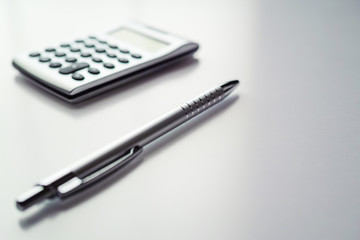 灰色基調のメタリックなボールペンと電卓