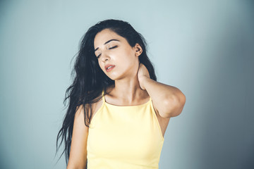 Woman suffering from neck pain on gray background