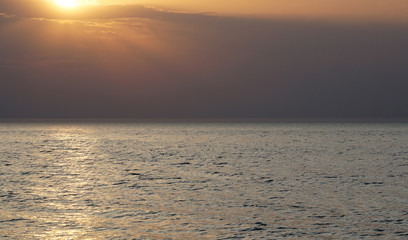 Empty sea to the horizon, evening. The sun is approaching the horizon, a light path is visible on the water.