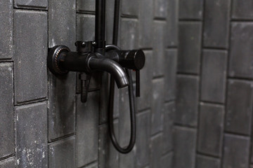 shower mixer on rough dark grey brick wall