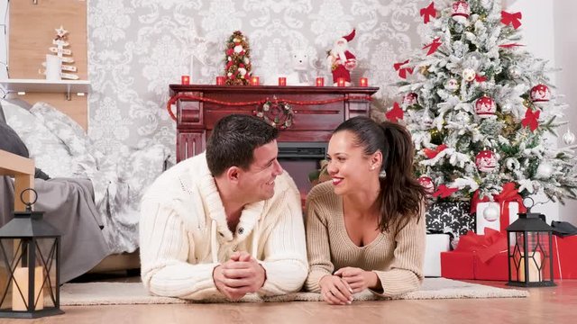 Couple on the floor laughing and having a good time in Christmas eve. There is a fireplace in the background
