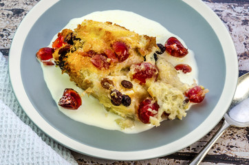 Freshly baked bread and butter pudding served on a plate with cream. 