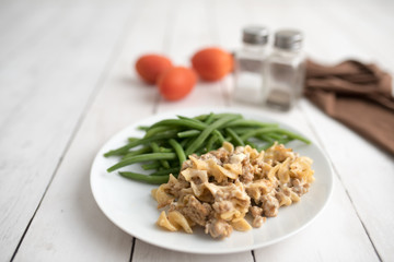 Turkey Stroganoff on white wood table with green beans and seasonings